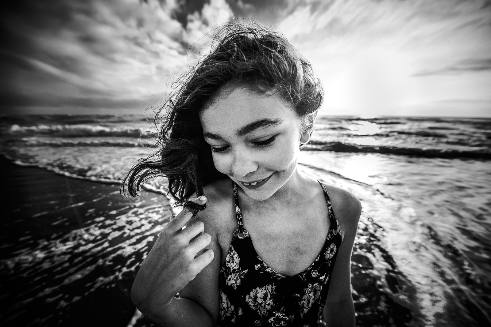 Black and white portrait of a young girl at the beach with wind in her hair and sunlight behind her, awarded Best Black & White by Click Pro