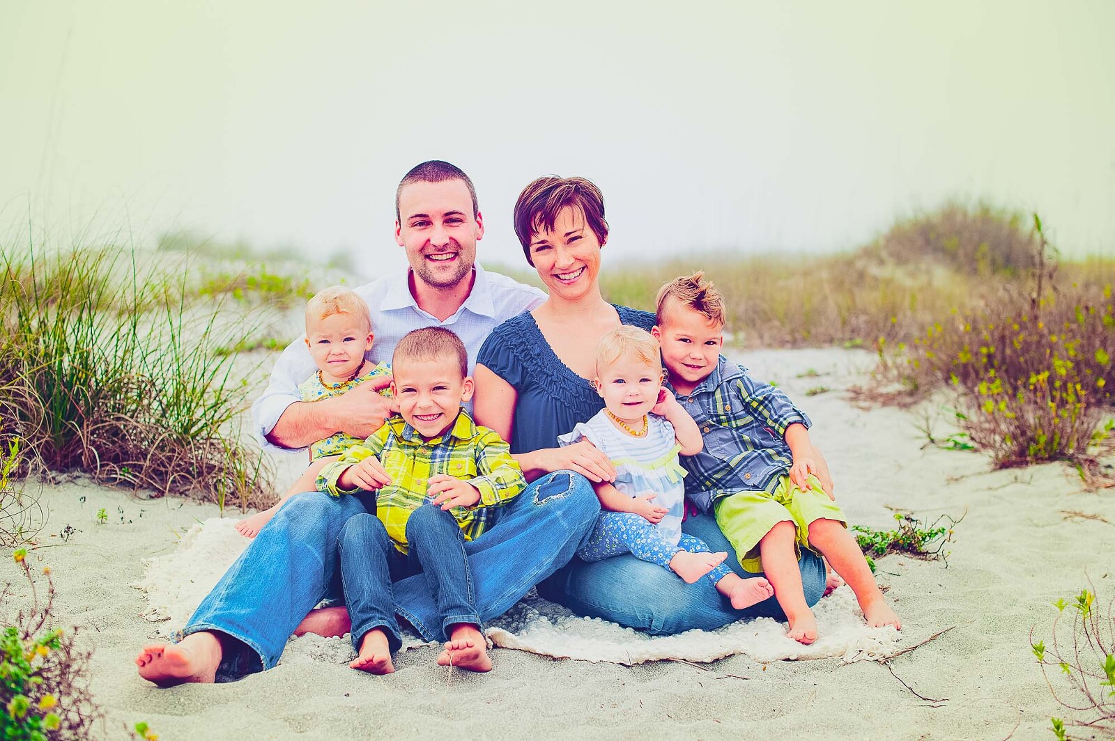Family of six sitting on blanket at Sarasota beach during golden hour on an overcast day