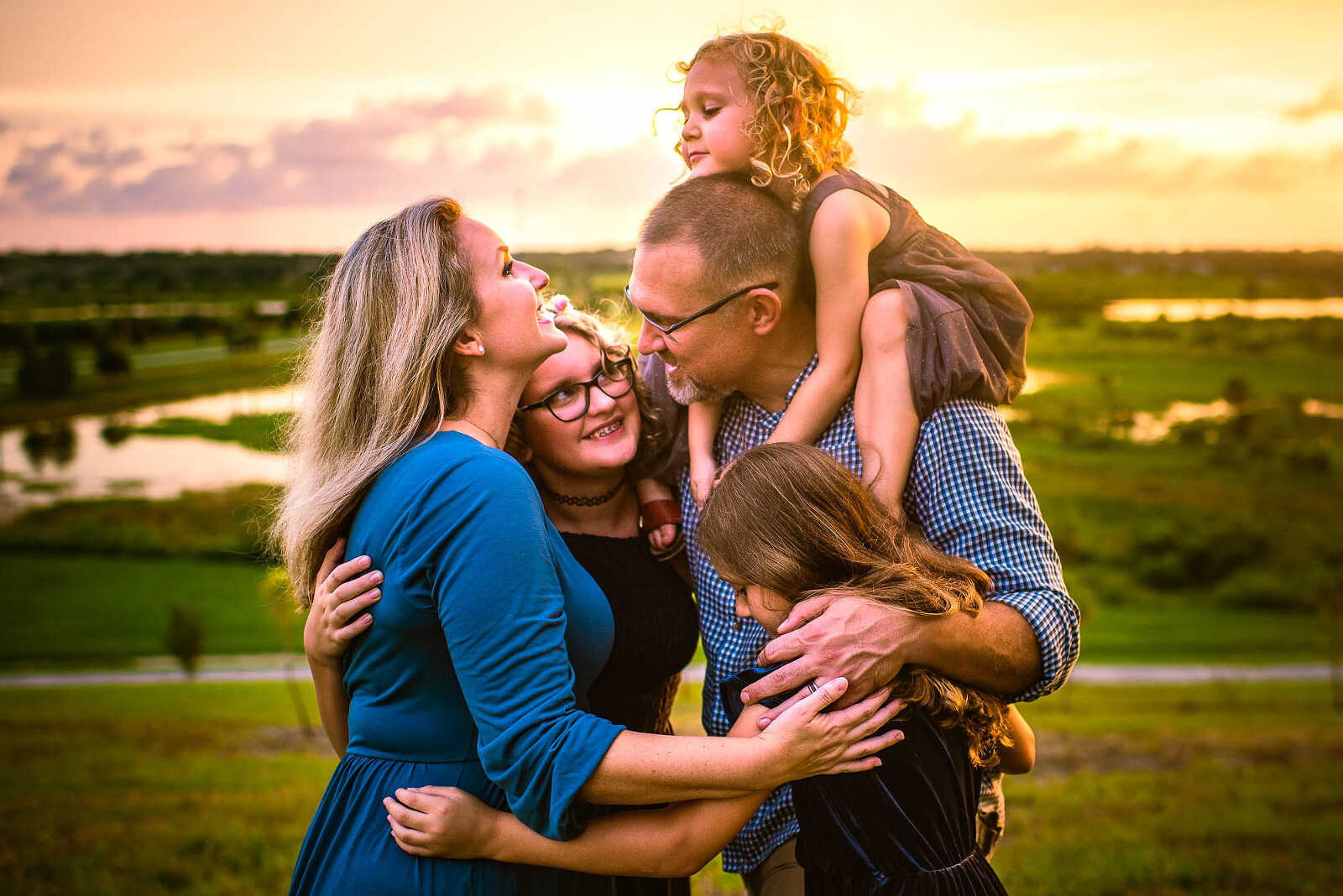 Family embracing at golden hour near Sarasota wetlands with joyful expressions