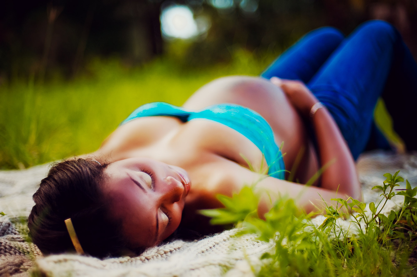 Pregnant woman lying on a blanket in the grass, bathed in sunlight during a Sarasota maternity session