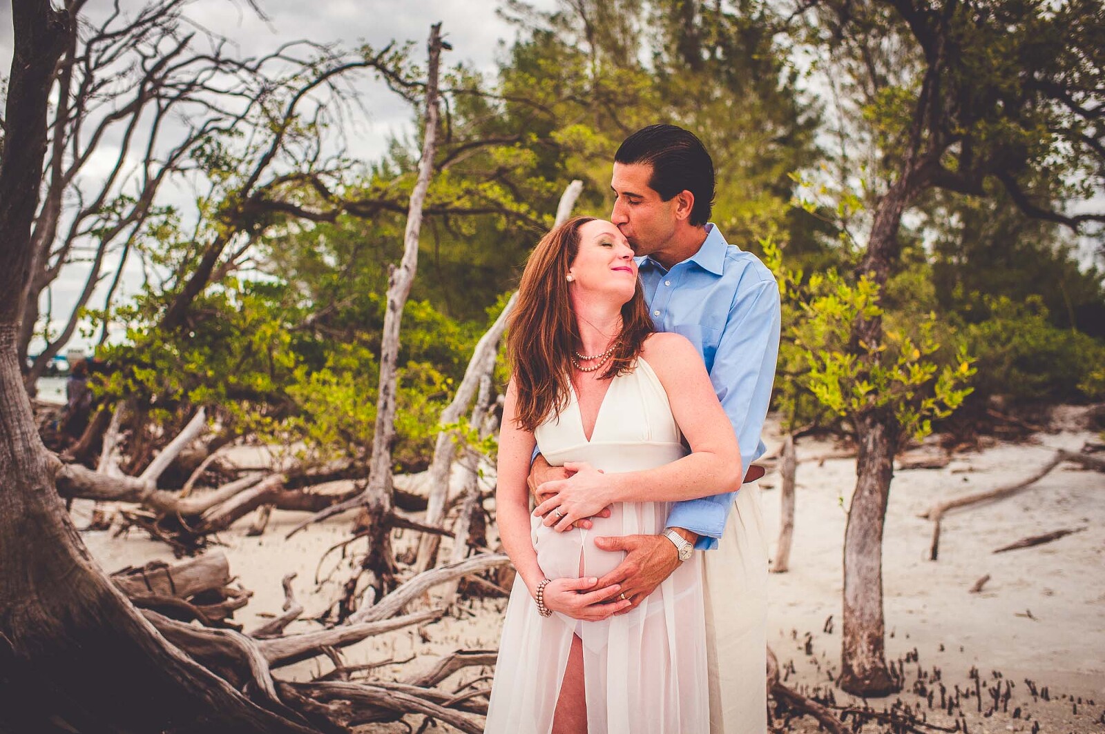 Couple embracing at the driftwood beach during a maternity session in Sarasota